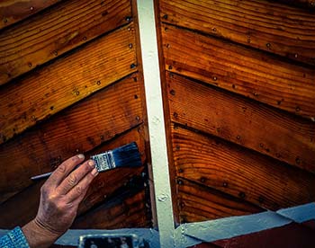 homme en train de lasurer des planche de bois