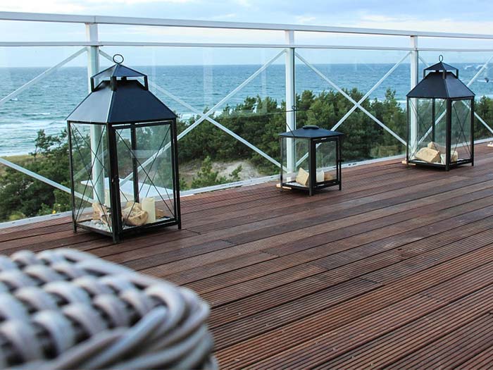terrasse bois en bord de mer avec lanternes posées sur la terrasse