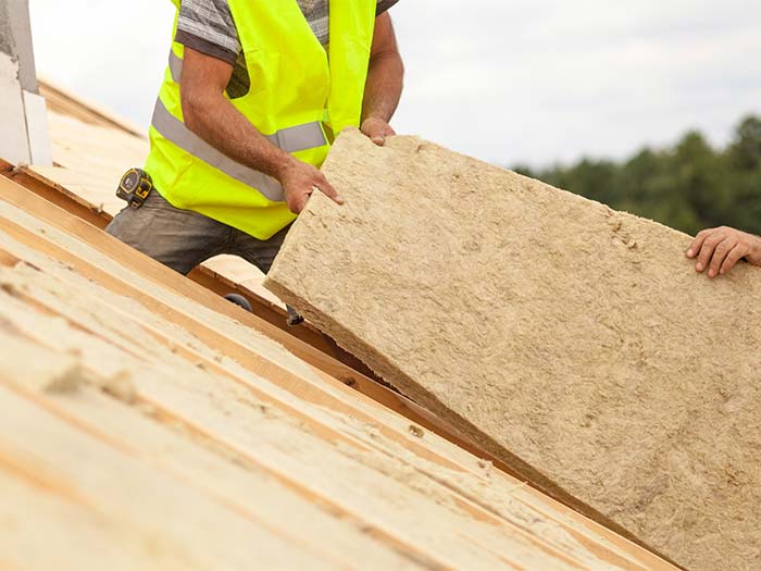 homme en train d'installer de la laine de roche pour isolation sous toit